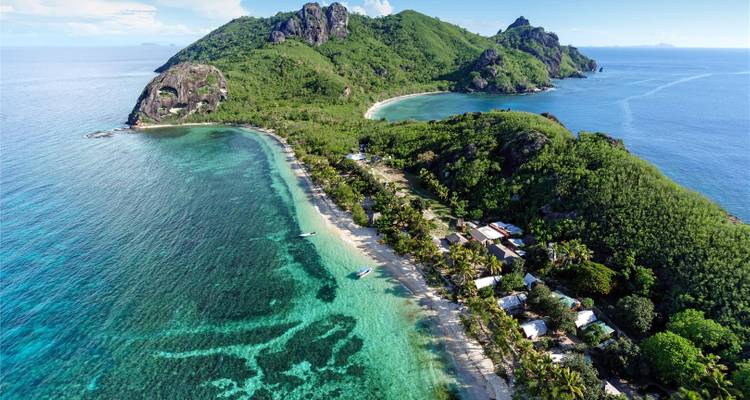 Vue aérienne d'une île verdoyante entourée de récifs coralliens vibrants et de lagon turquoise dans le Pacifique Sud.