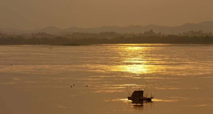 Goldenes Sonnenlicht, das sich auf dem Wasser mit entfernten Hügeln spiegelt.
