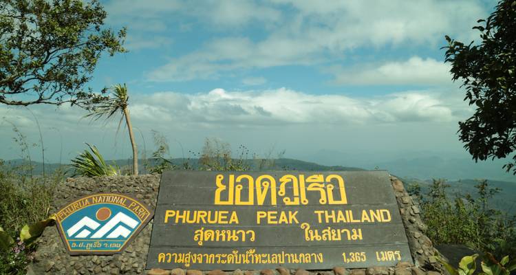 Schild am Phu Ruea Peak mit den Bergen im Hintergrund.