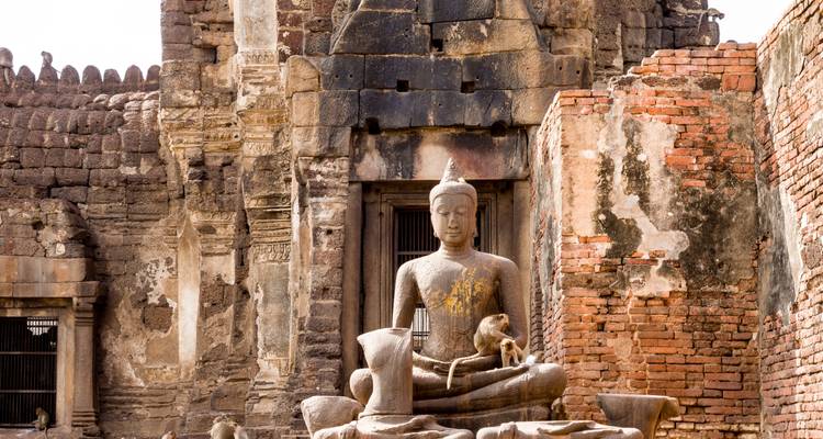Buddha-Statue an einer historischen Stätte mit Steinmauern.