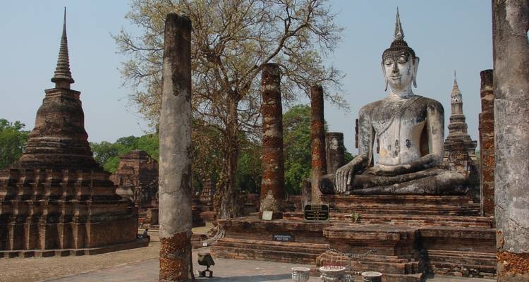 Gran estatua de Buda sentado entre ruinas antiguas.