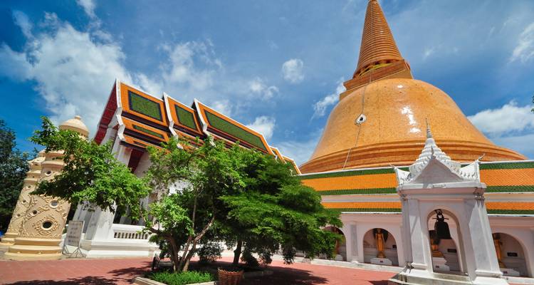 Große orangefarbene Stupa mit Tempelstrukturen unter blauem Himmel.