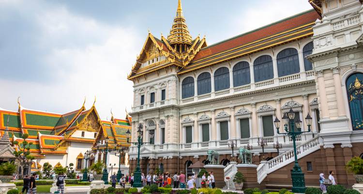 Vue extérieure des bâtiments du Grand Palais de Bangkok avec des toits ornés et des touristes dans la cour