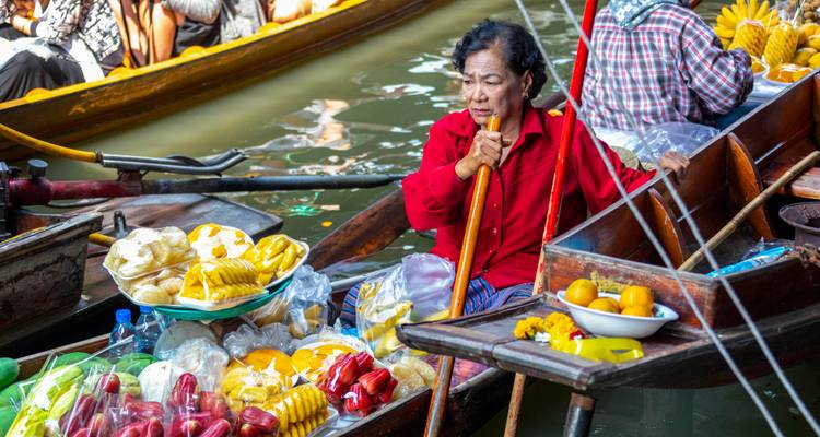 Vendeuse dans une barque en bois vendant des fruits tropicaux frais au marché du canal.