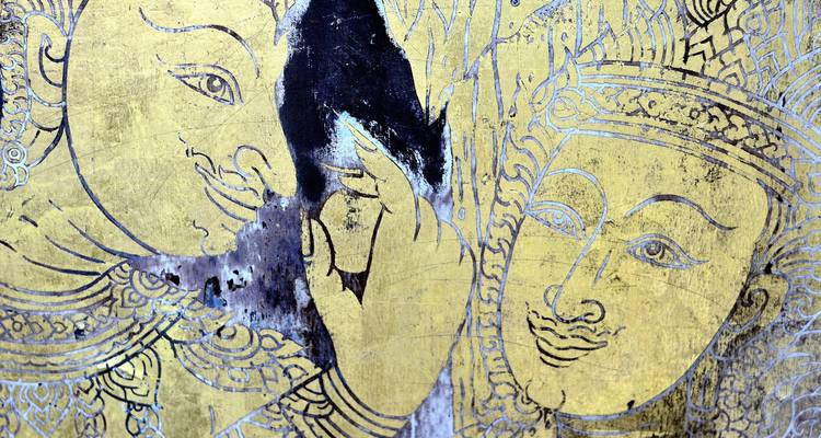 Gros plan sur une œuvre d'art traditionnelle or et noire représentant des visages.
