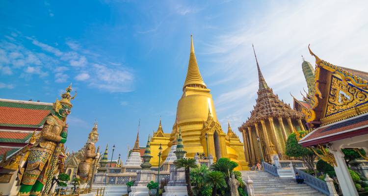 Temple doré élaboré avec des statues de gardiens dans un cadre serein.