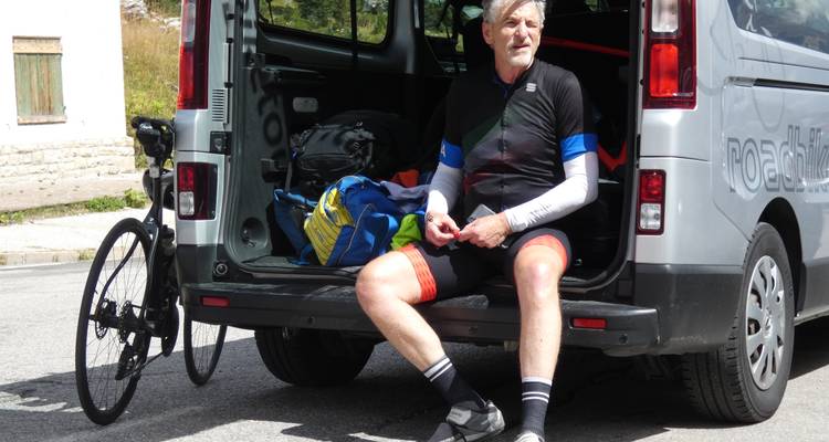 Ciclista descansando en la parte trasera de una furgoneta con equipo de ciclismo.