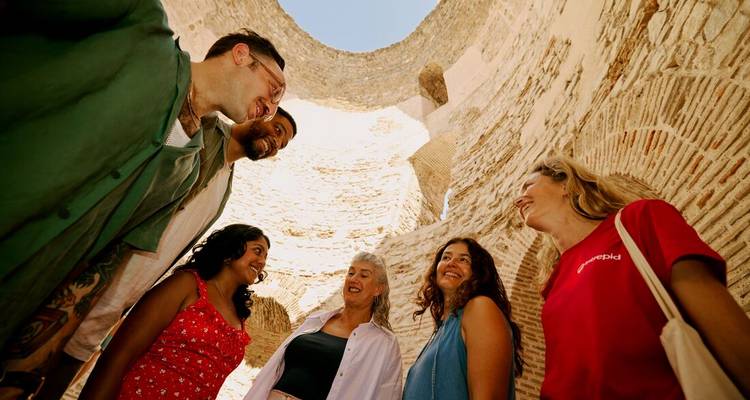 Groupe de touristes à l'intérieur d'une structure en pierre ancienne regardant vers le haut.