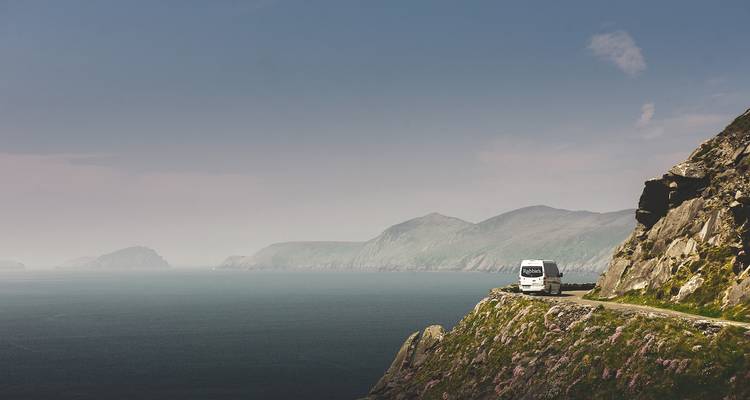 Reisebus auf einer Küstenstraße mit Blick auf das Meer.