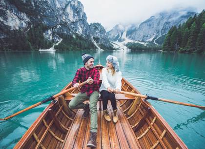 A couple rowing a boat together as they gaze out to the mountains and the beautiful Alaskan scenery