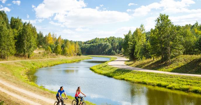 A pair of cyclists on a bicycle tour with a river cruise