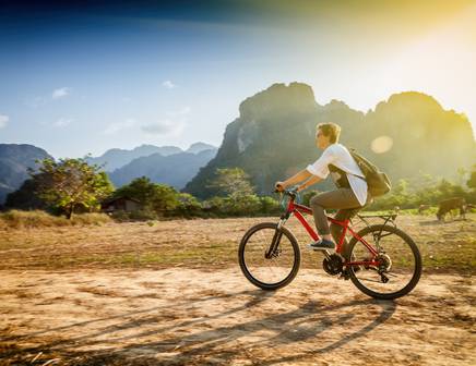 A man riding his bicycle near a cliff with panoramic views