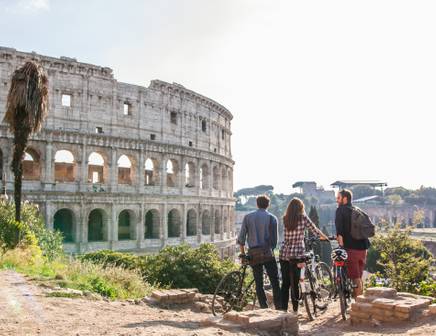 a couple of friends cycling together next to the roman colosseum