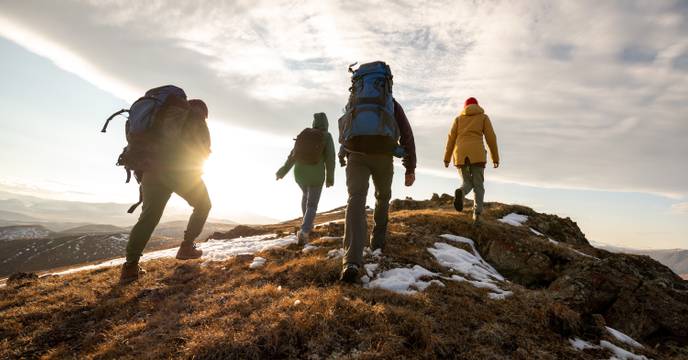 a group of hikers travelling together and trekking up a mountain peak