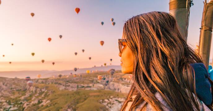 a woman gazing out over the hot air balloon skies of cappadocia, turkey