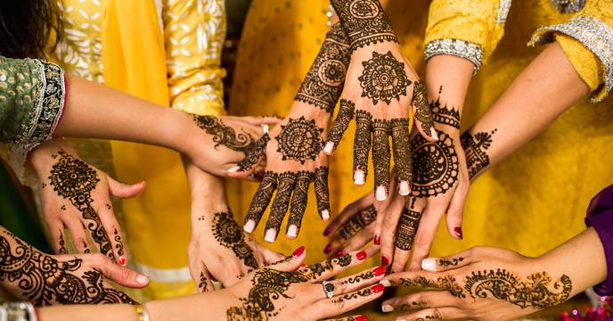 close up of mehndi art on the hands of travellers wearing traditional dress in india