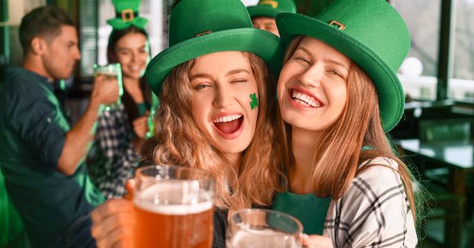 Two girls celebrating St. Patrick's Day at an Irish Pub together whilst drinking a Guiness