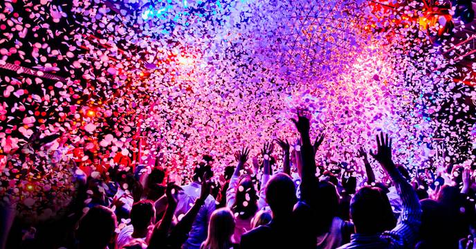 A group of festival goers dancing underneath confetti at an electronic music concert