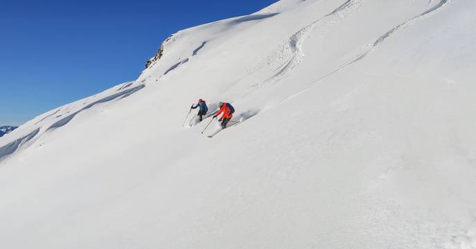 Two people skiing down a snowed hill