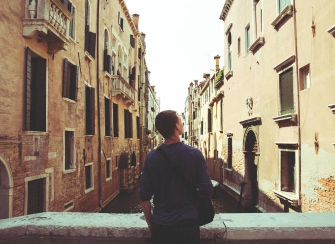 Male tourist enjoying the view of a canal in Venice.