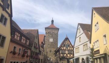 A historic walled city entrance with tower and half-timbered buildings.