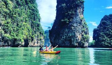 People kayaking between scenic rock formations on a calm day.