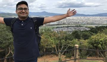 Man posing with a view of a city and mountains.