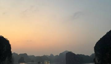 Sunset over a tranquil bay with limestone formations.