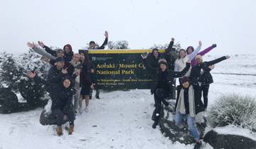 Group of people posing in front of a snowy park sign.