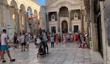 Historic square with a crowd and a stone building.