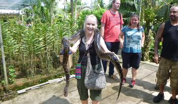 A woman holding a python in a garden setting.