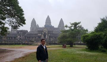 A visitor at Angkor Wat surrounded by lush greenery.