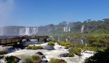 Tourists on a platform overlooking Iguazu Falls with lush greenery.