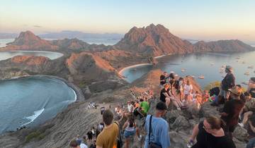 Crowd on a rocky cliff with scenic background.