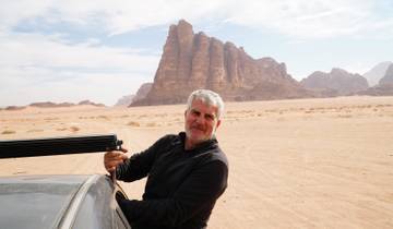 A man standing next to a vehicle in a desert landscape.