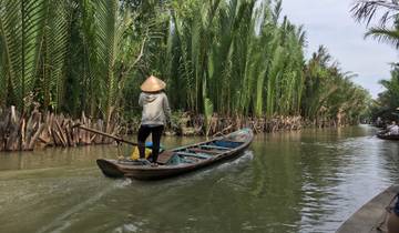 Person paddling a boat through a palm-lined canal.