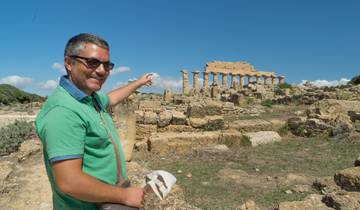 Smiling man pointing at ancient temple ruins.
