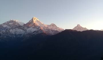 Mountain landscape at sunrise with peaks illuminated by the sun.