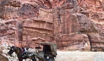 Horse-drawn carriage in front of large red rock formations.