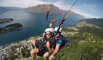 Paragliders soaring over a lake with a mountainous backdrop.