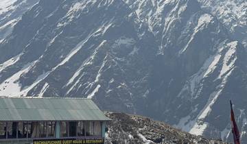 Mountain cabin with backdrop of steep rocky mountains.