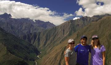 Three people posing in front of a mountain landscape.