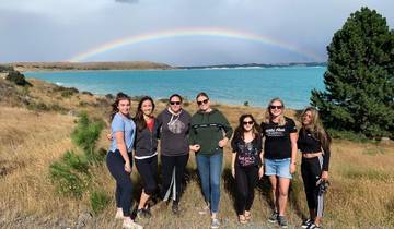 Group pose in front of a lake with a rainbow in the sky.
