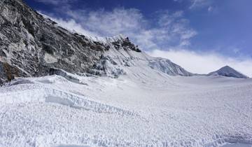 A vast expanse of snow-covered mountains under a blue sky.