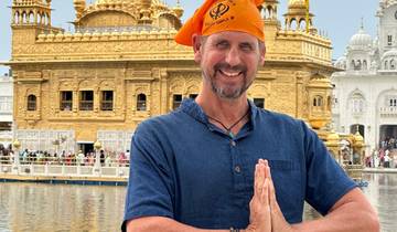 Man posing in front of a golden temple.