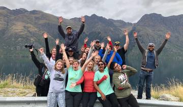Group of people celebrating with raised hands in a scenic mountainous area.