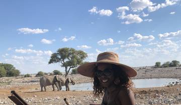 Woman wearing a hat with elephants in the background.