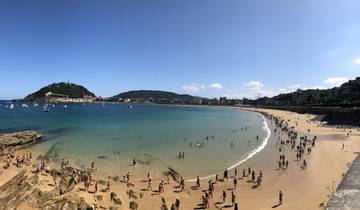 Panoramic view of a crowded beach with hills in the background.