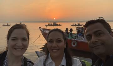 Group of people on a boat at sunset with other boats in the background.