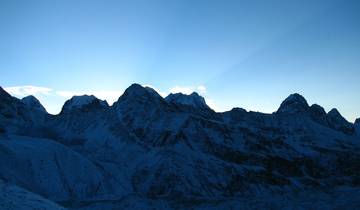 Silhouette of snow-capped mountains at sunrise.